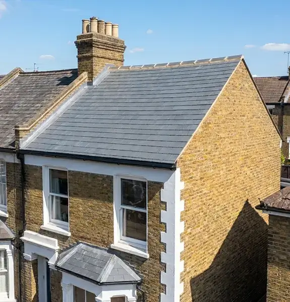 New grey tiled roof alongside the old worn roof it replaced